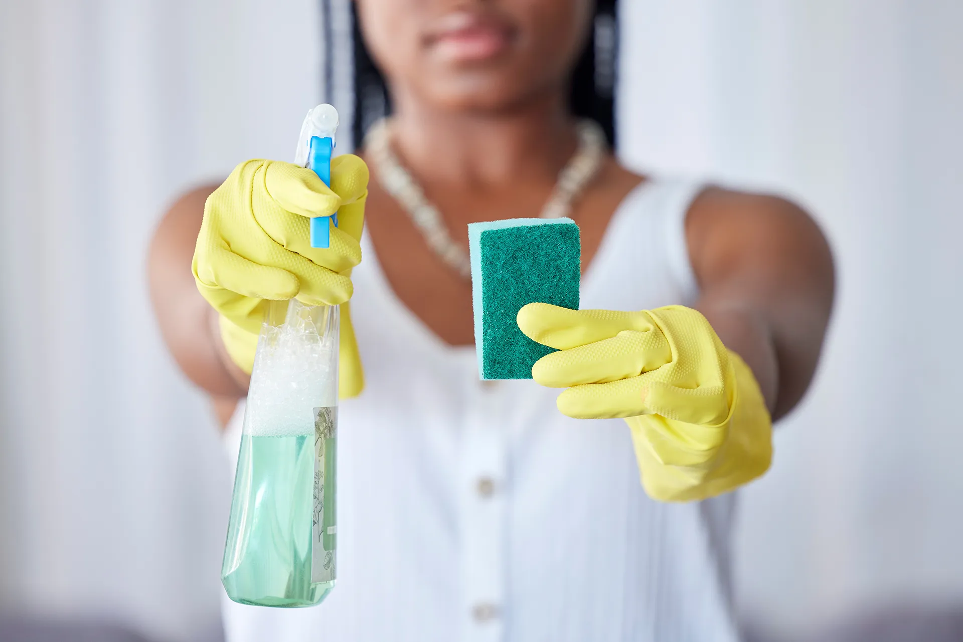 Professional Household Cleaning worker showing a spray bottle and sponge